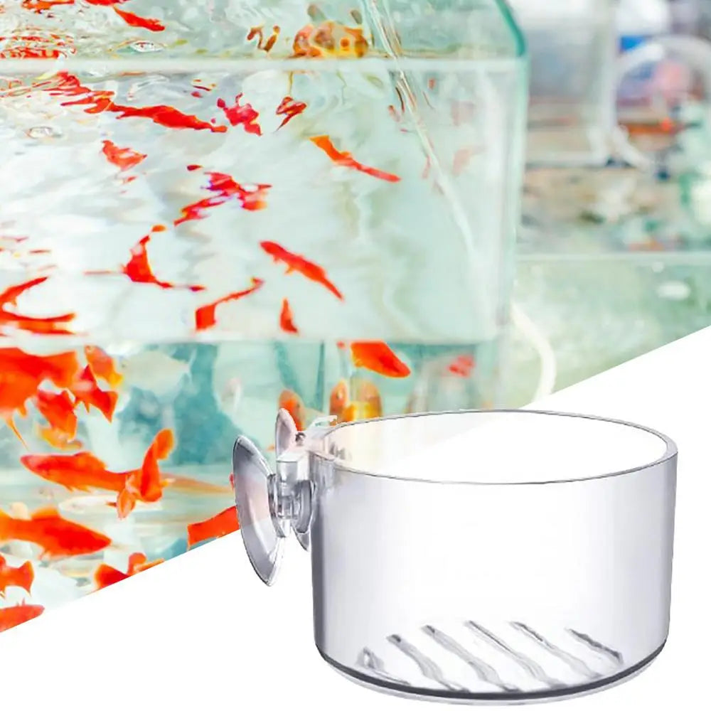 Clear fish tank filter with suction cup against a blurred background of goldfish in water.