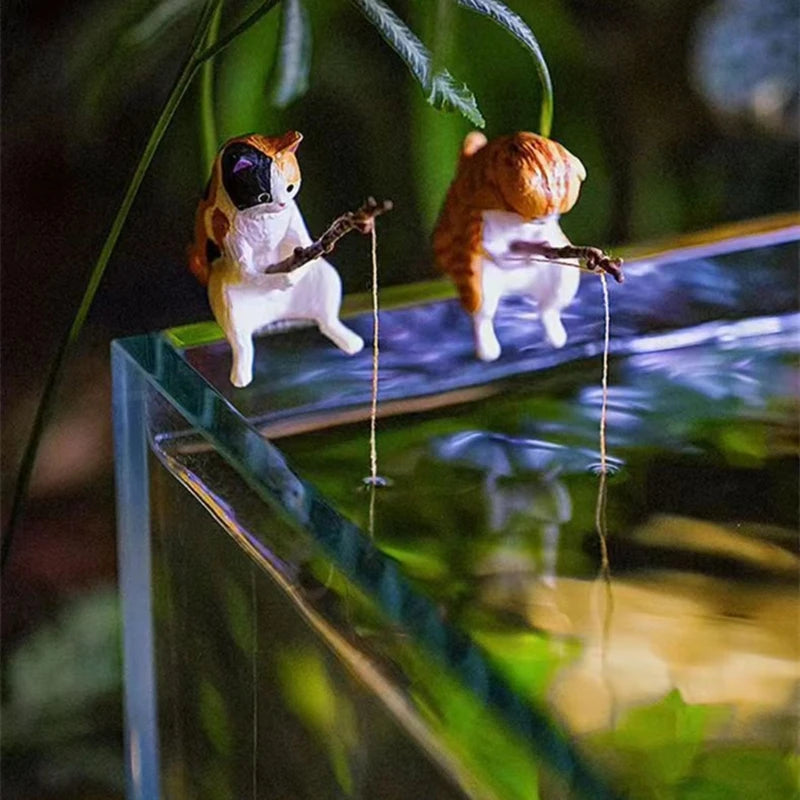 Two small dog figurines playing guitar and drums on a reflective surface with plants in the background.