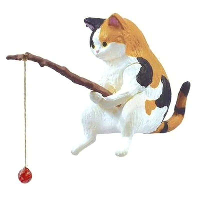 Cat figurine with a branch and red ball on a white background