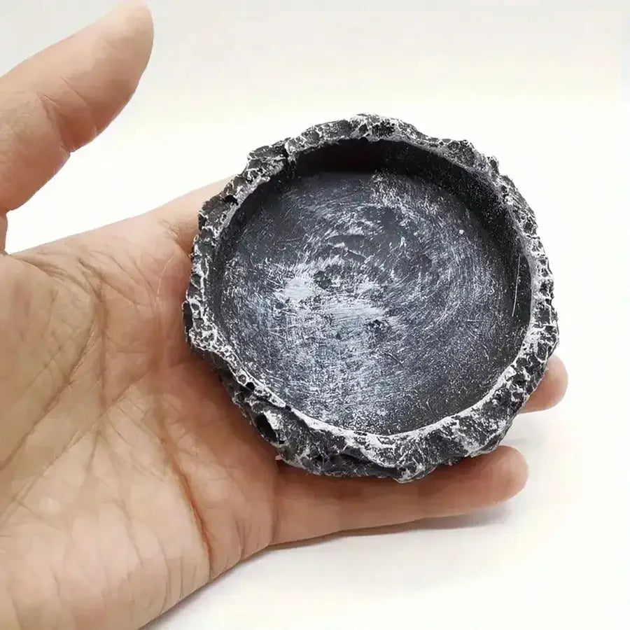 Hand holding a textured stone bowl against a white background