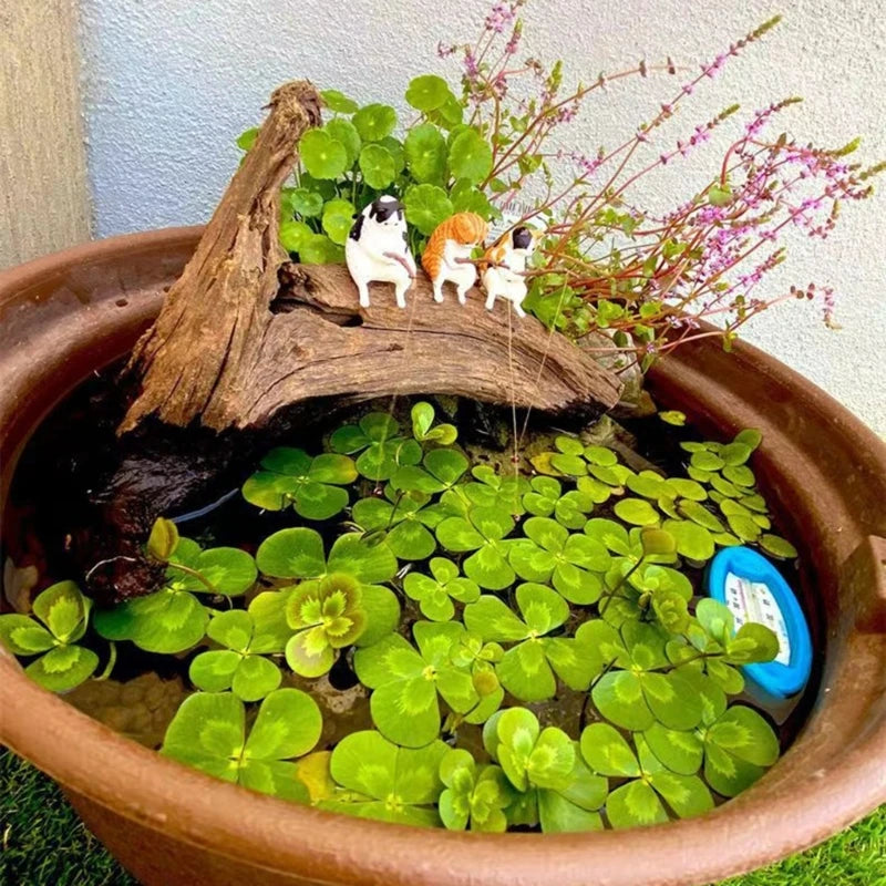 Miniature pond with decorative elements including a log, small figurines, and plants.