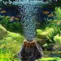 Aquarium with fish, plants, and a stone with air bubbles.