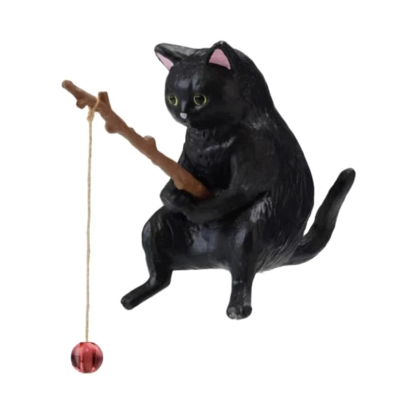 Black cat figurine with a string toy on a white background