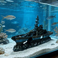 Model of a battleship in an aquarium with fish and underwater plants.