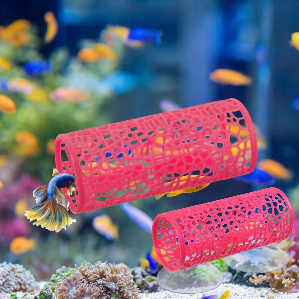 Two red cylindrical fish tanks with a lattice cutout design, shown in an aquarium setting with a live betta fish swimming through the top one and a coral stand supporting the bottom one.