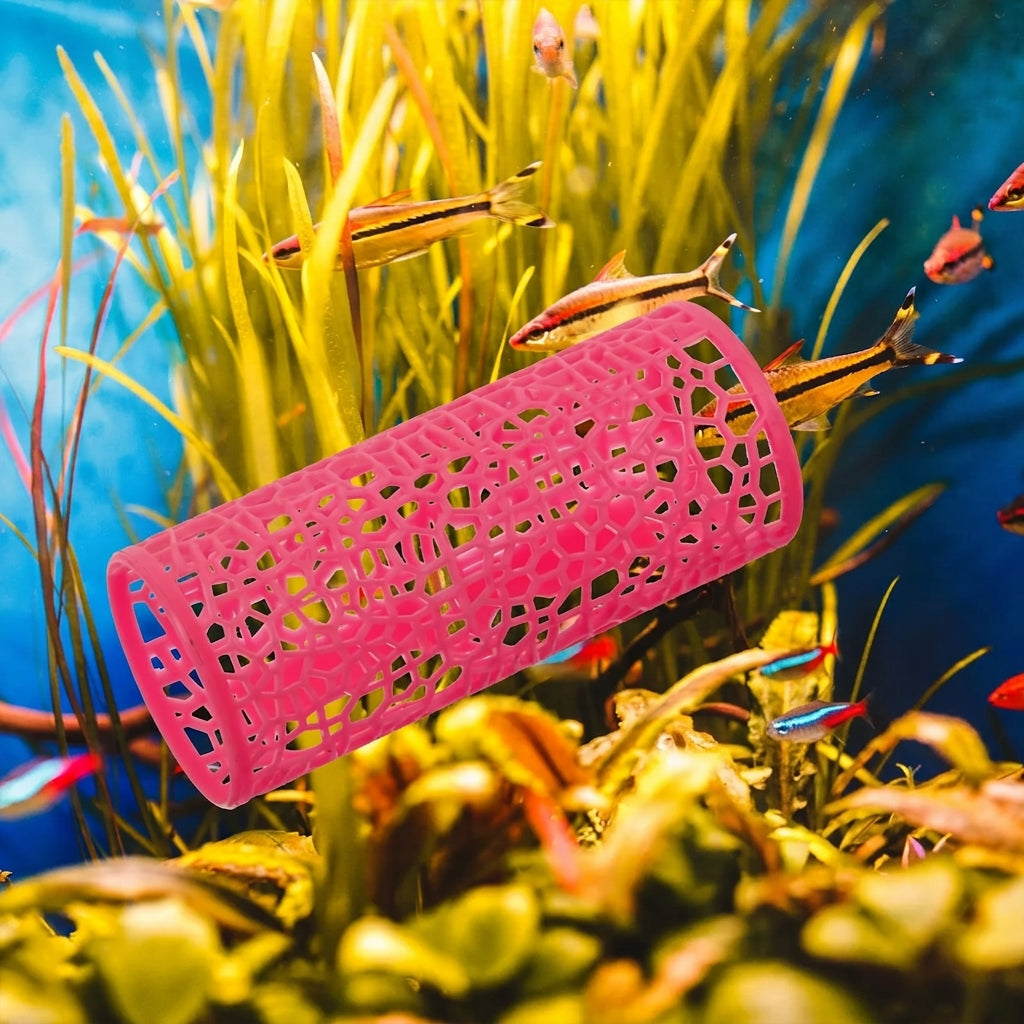 A bright pink cylindrical mesh filter or skimmer basket floating in an aquarium filled with yellow aquatic plants and small fish.